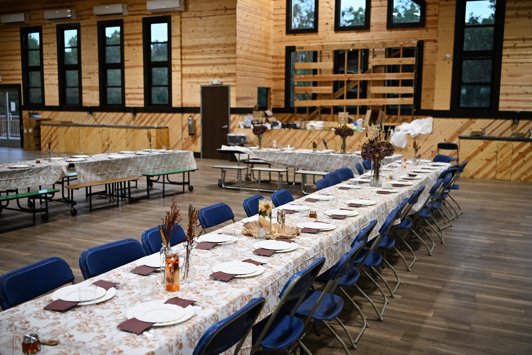 The wood-paneled dining hall set for a Yom Tov meal — long tables, flowers and place settings