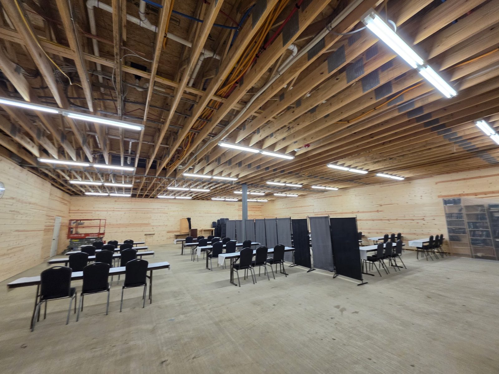 The big wood-lined hall where davening and hakafos happen — rows of tables and chairs under exposed beams